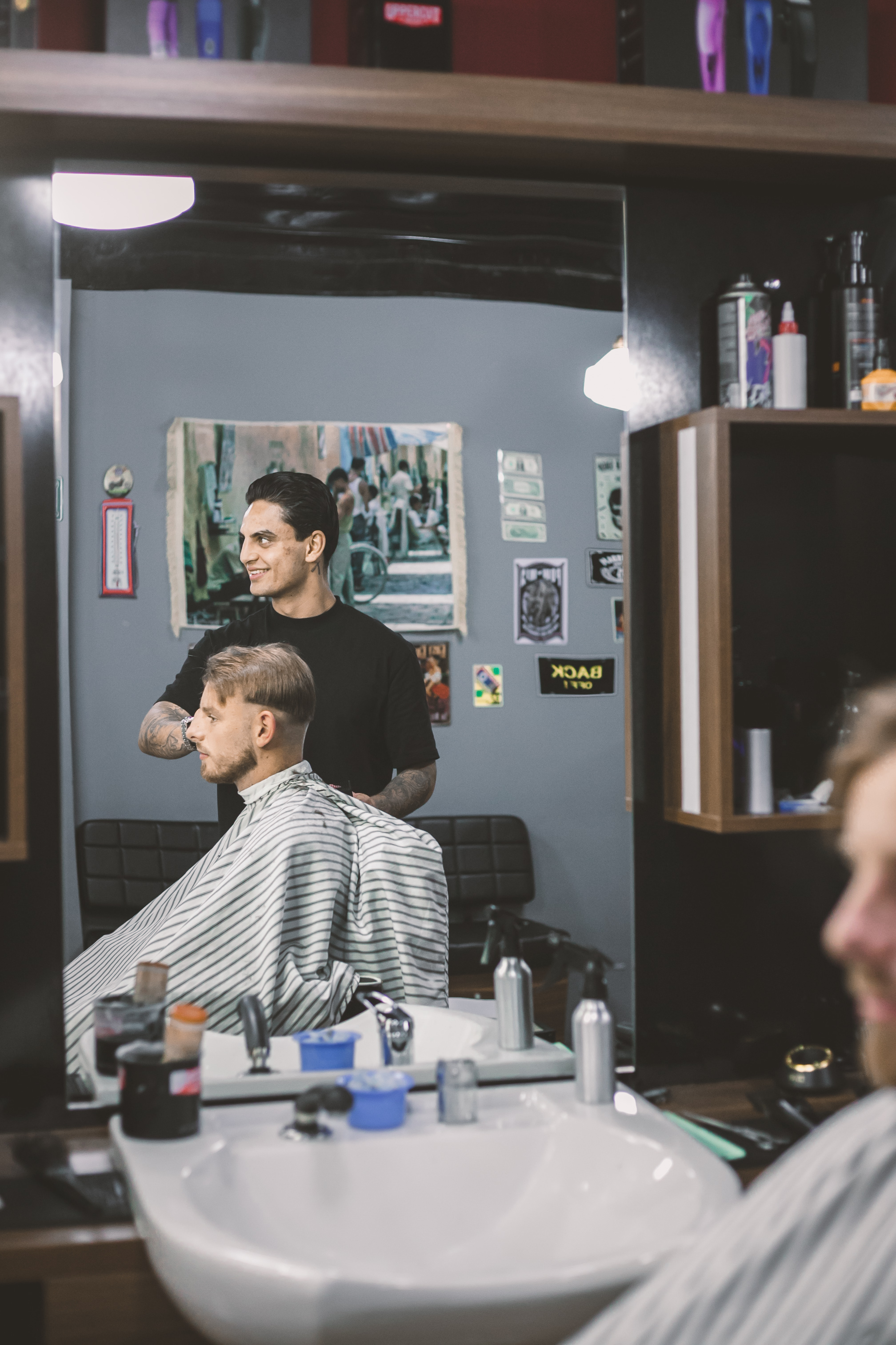 Barbier en klant in de spiegel, met de wasbak op de voorgrond